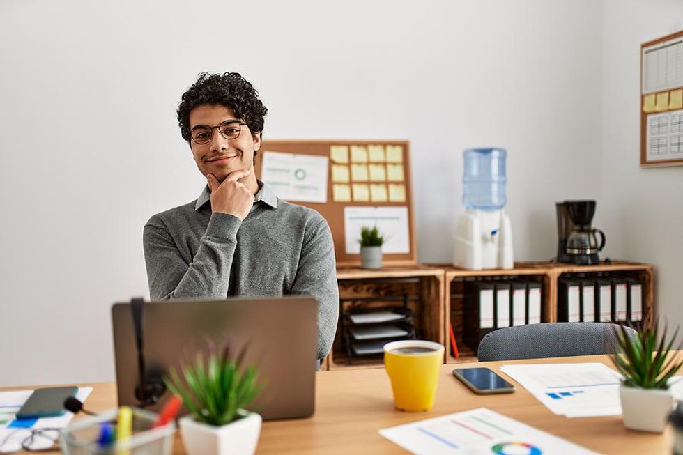 Happy man on laptop thinks about solving problems at work