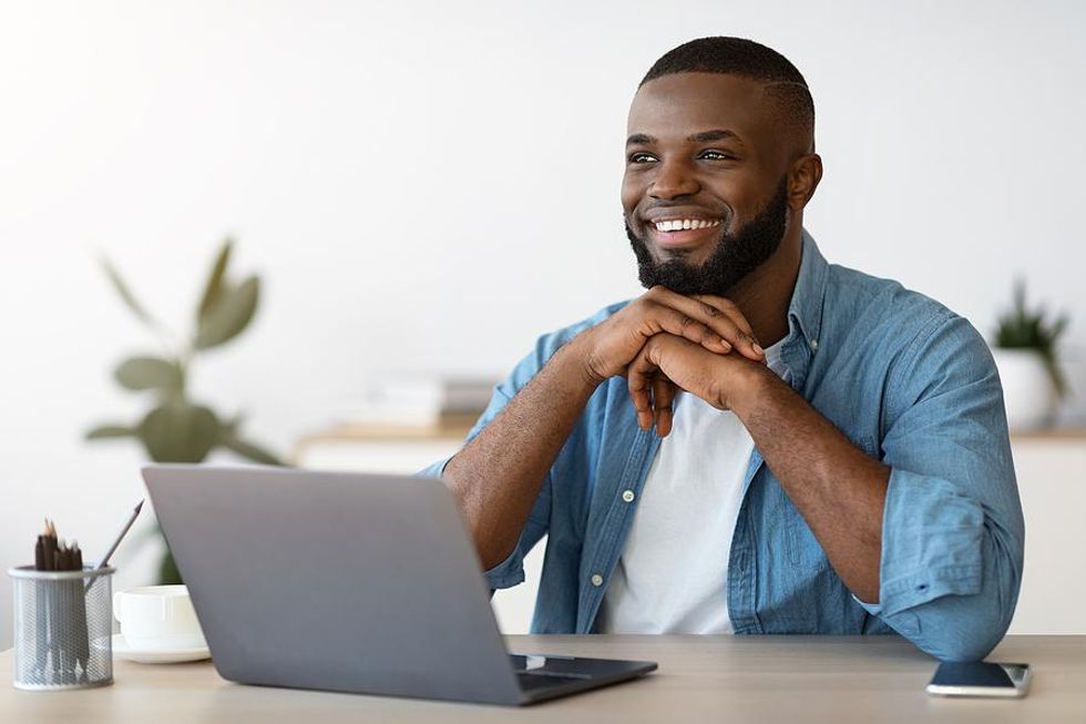 Happy man on laptop working from home with a flexible work schedule