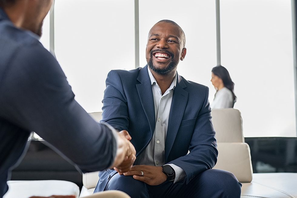 Happy man shakes hands with someone as he networks to improve his career