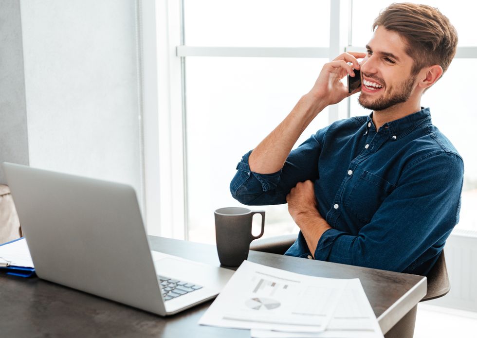 Happy man talks on the phone at work