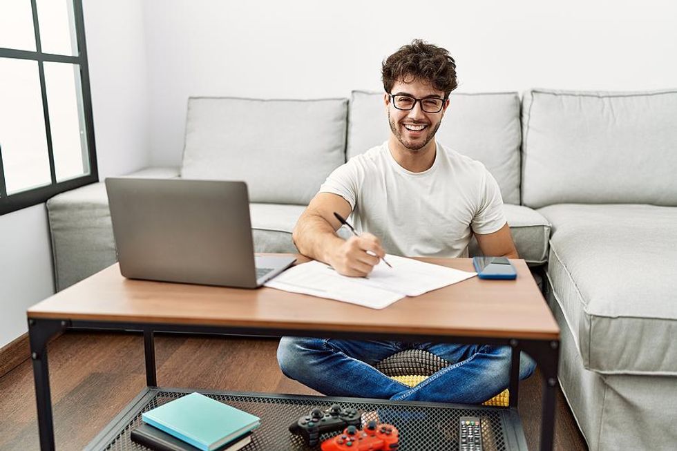 Happy man writing and using his laptop looks for a job