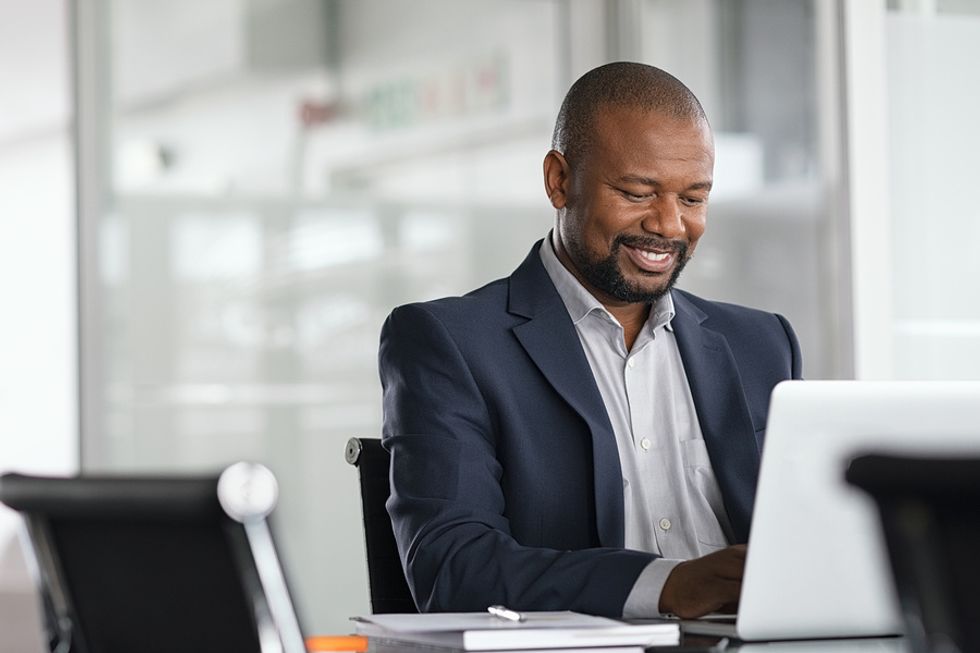 Happy professional man writes a cover letter on his laptop