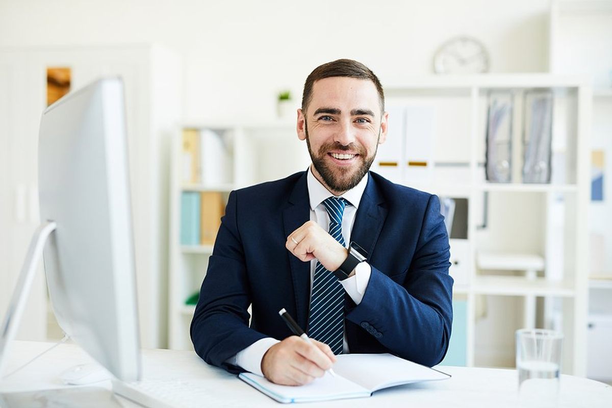 Happy professional man writes down his goals at work