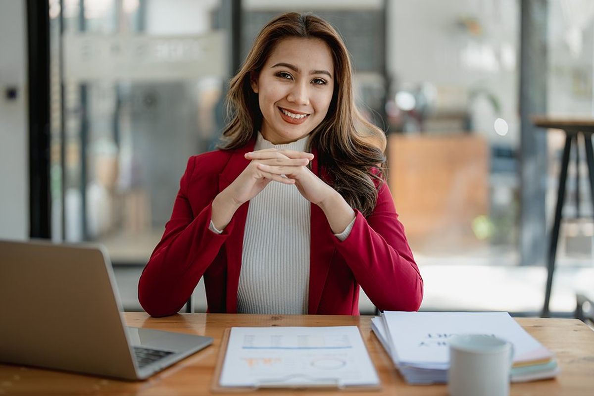 Happy professional woman sits at her desk at work