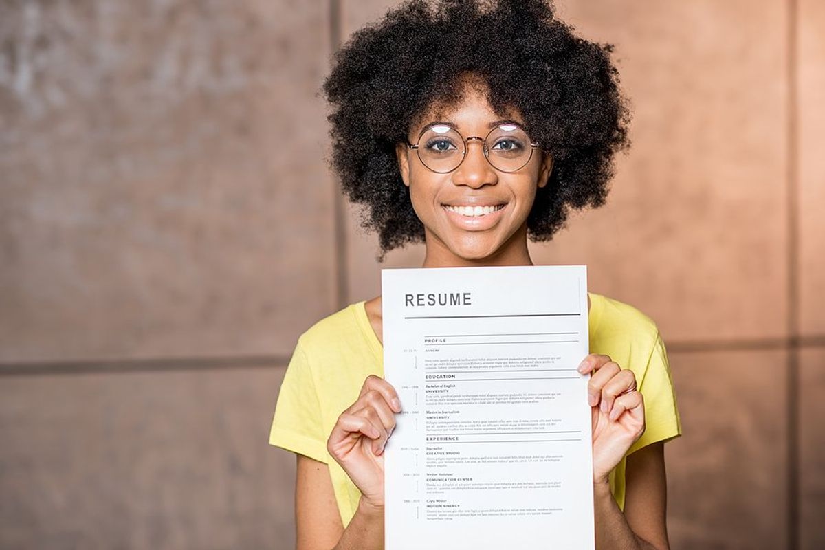 Happy woman holds up her resume after quantifying the information on it