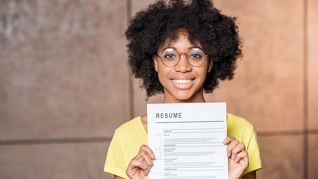 Happy woman holds up her resume after quantifying the information on it