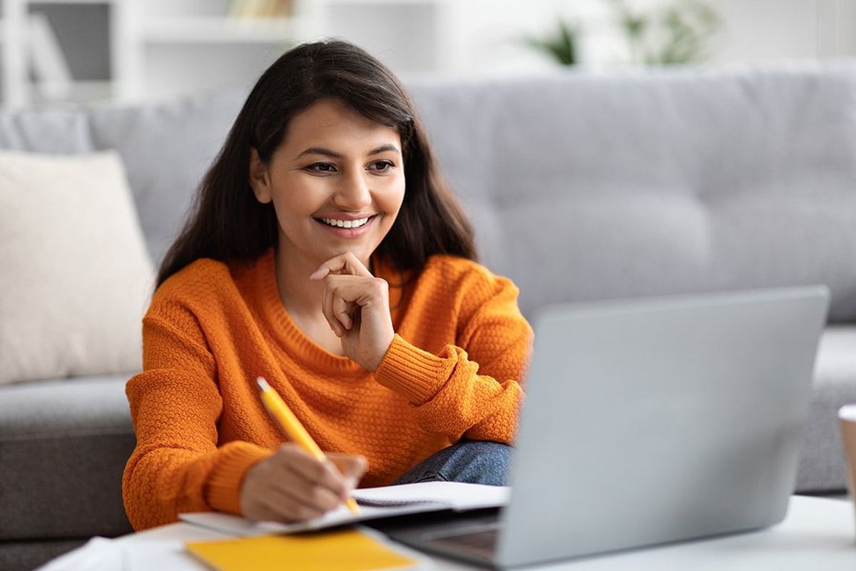 Happy woman on laptop learns how to upskill while not working her dream job