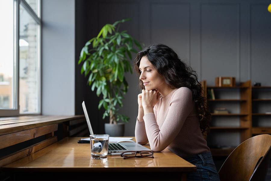 Happy woman on laptop looks for a job