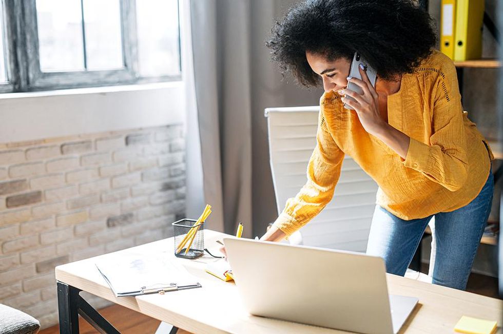 Happy woman on phone writes down her career goals at work