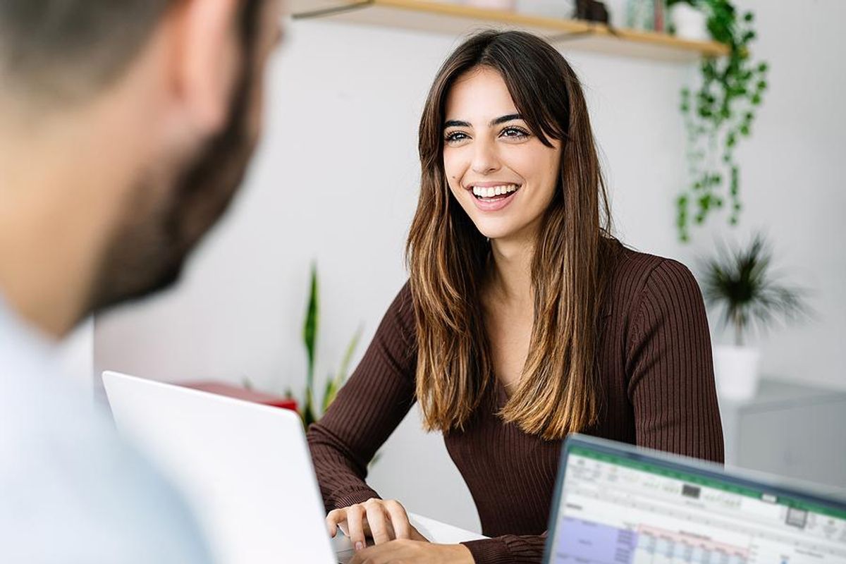 Happy woman smiles while talking to her coworker