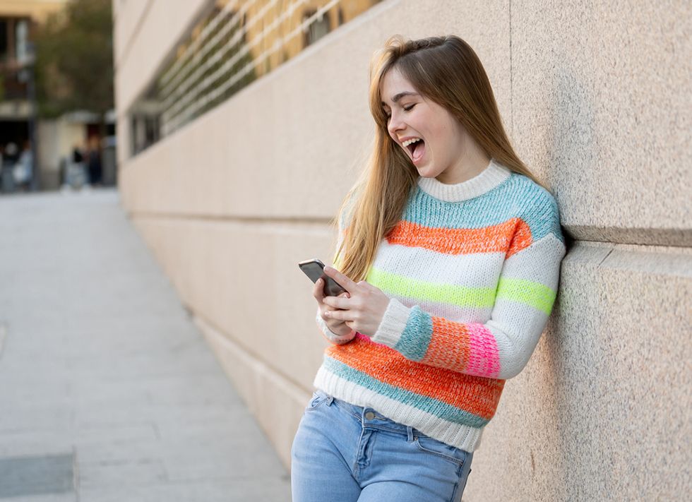 Happy young woman looking at her social media profiles on her phone