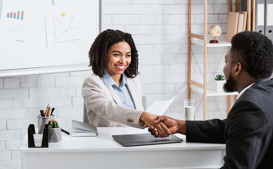 hiring manager shakes hands with a job candidate before an interview