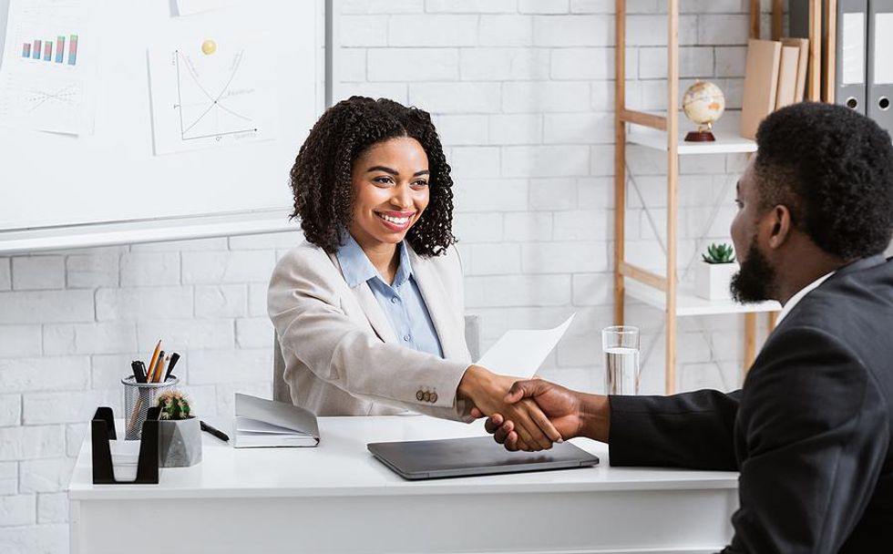 Hiring manager shakes hands with a job candidate before an interview