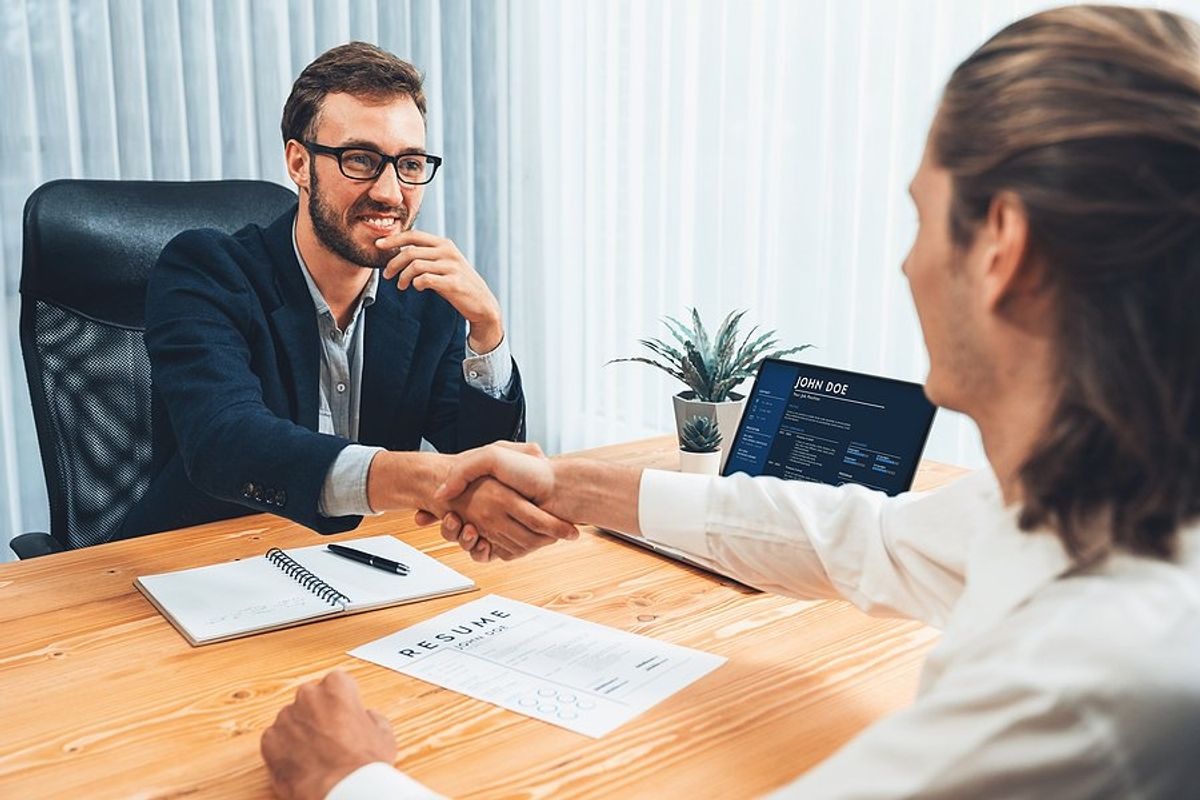 Hiring manager shakes hands with a job candidate before an interview