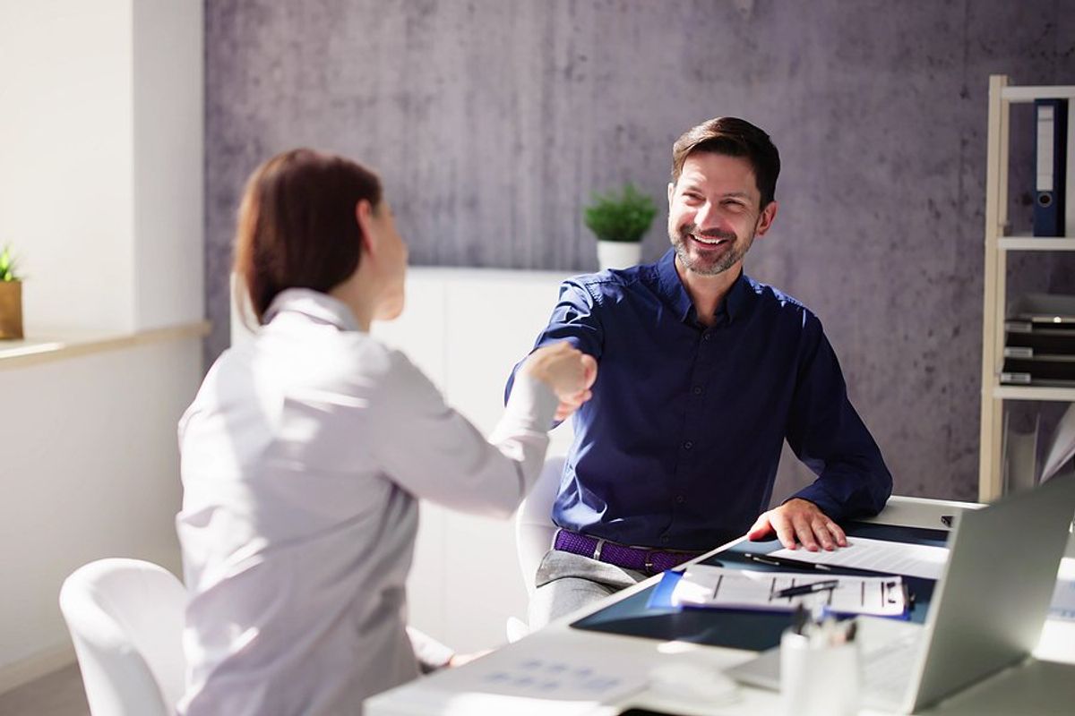 Hiring manager shakes hands with a job candidate before an interview