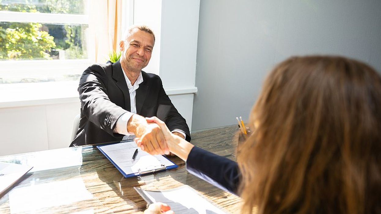 Hiring manager smiles and shakes hands with job candidate after a job interview