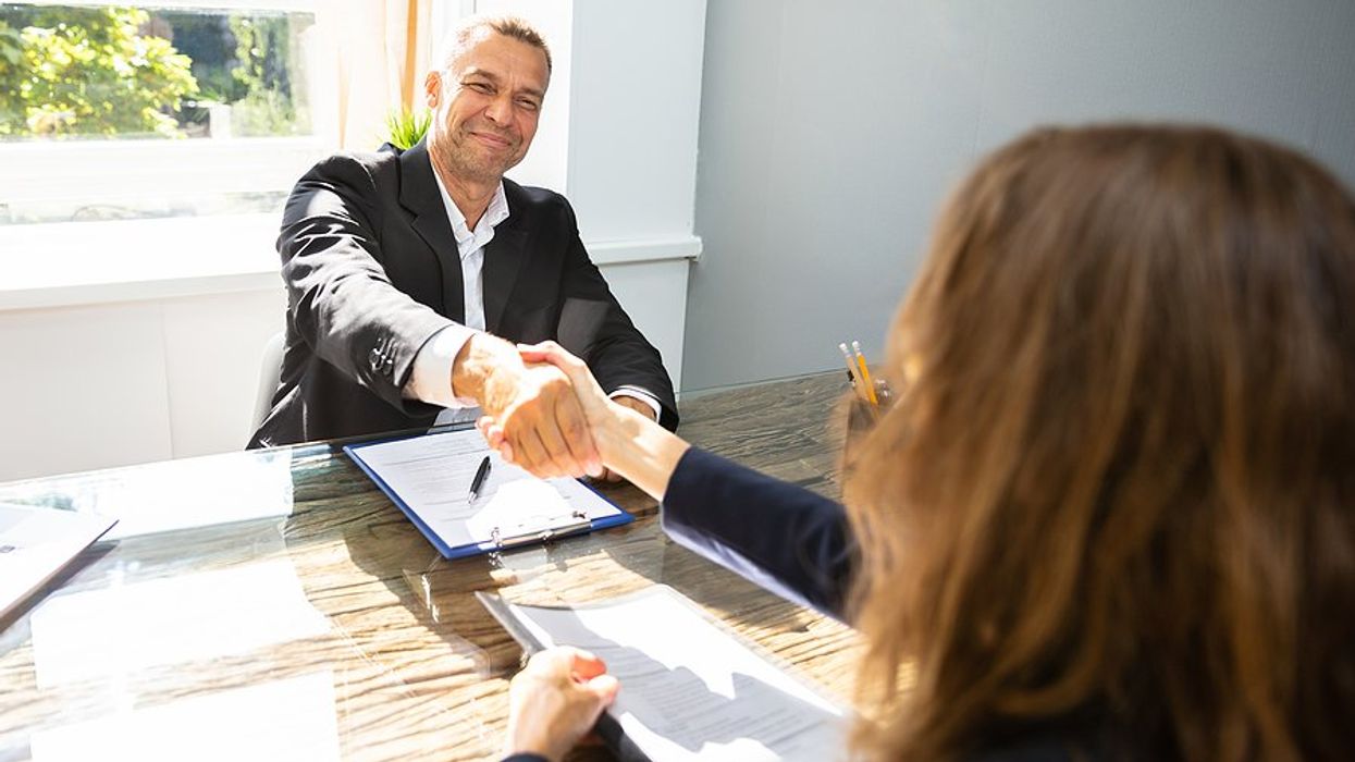 Hiring manager smiles and shakes hands with job candidate after a job interview