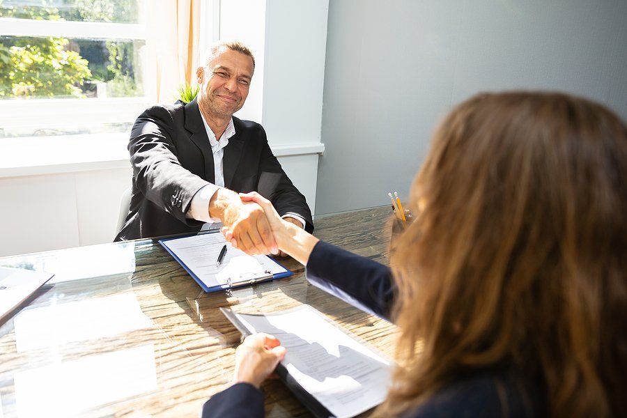 Hiring manager smiles and shakes hands with job candidate after a job interview