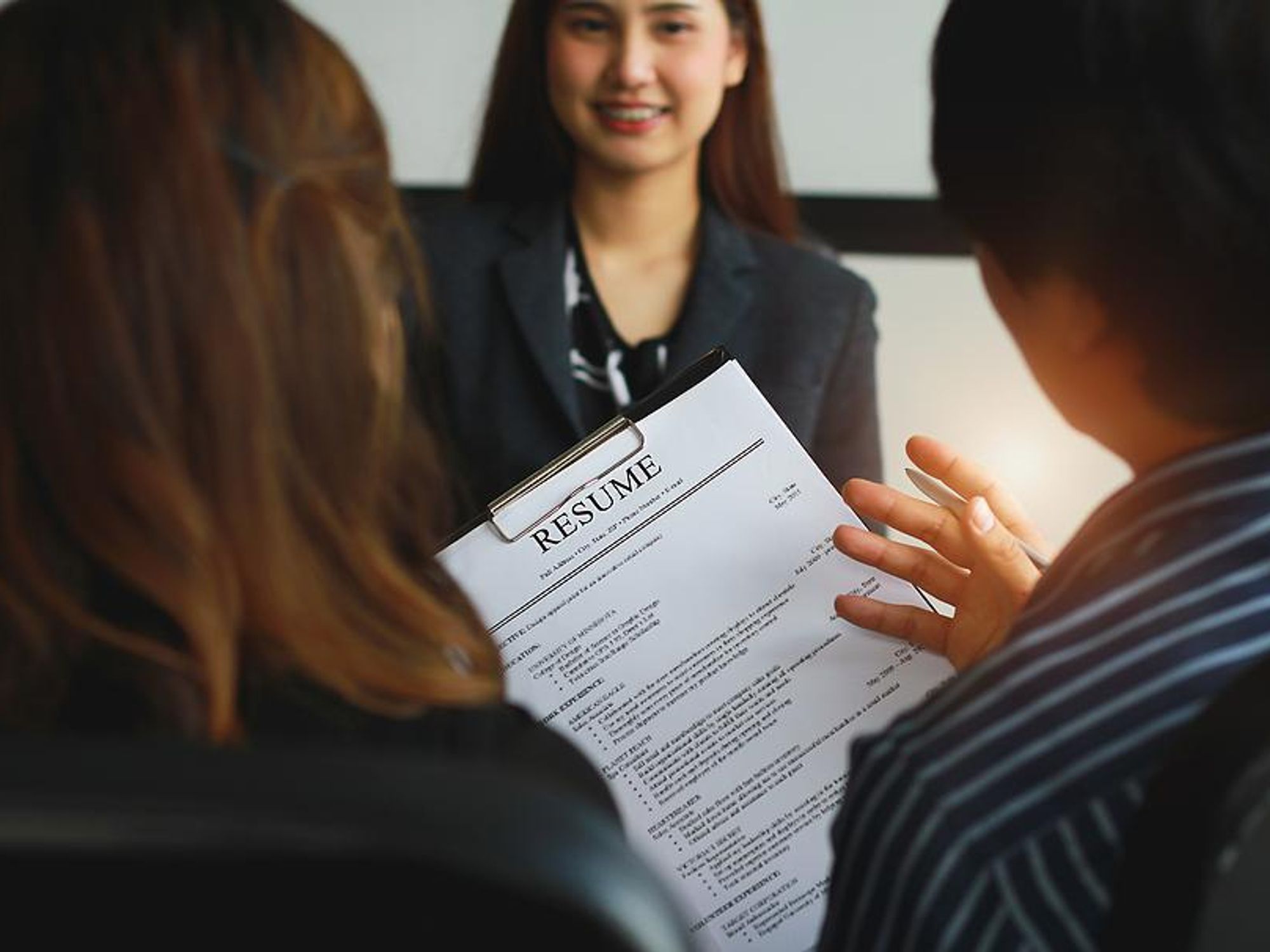 Hiring managers look at a job candidate's resume during an interview
