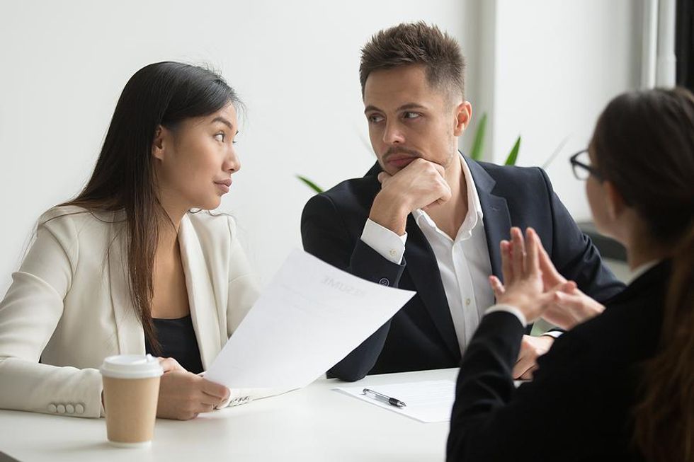 Hiring managers look at each other while interviewing a job candidate