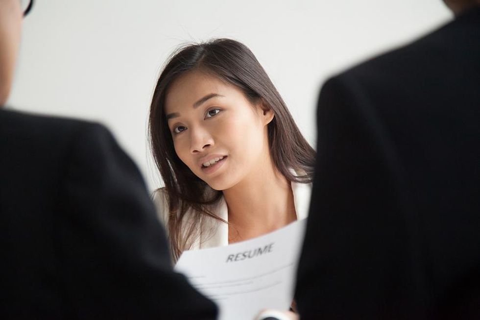 Hiring managers read a job applicant's resume during an interview