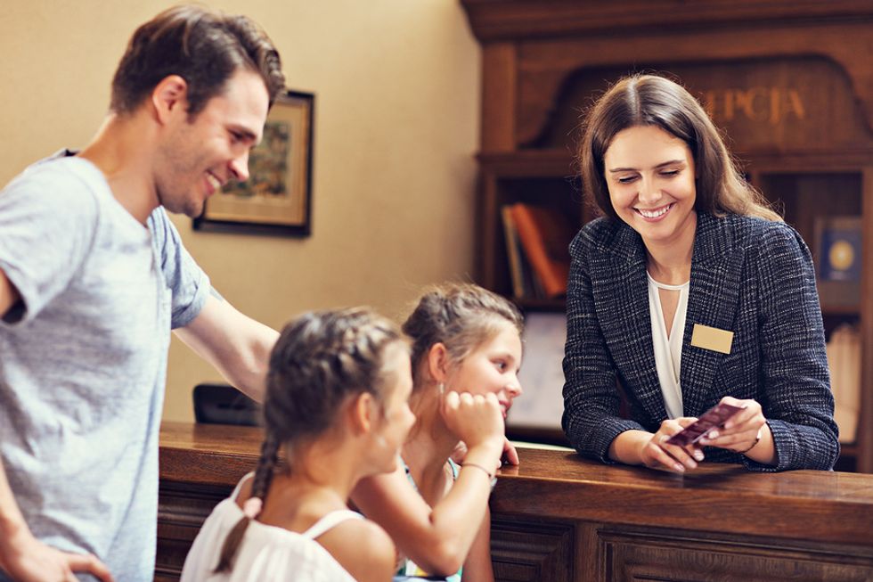 Hospitality worker checks customers in at a hotel.