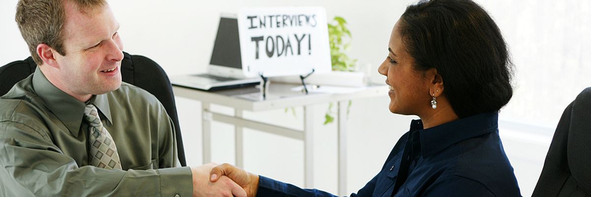Human resources associate shakes hands with a job seeker during an interview.
