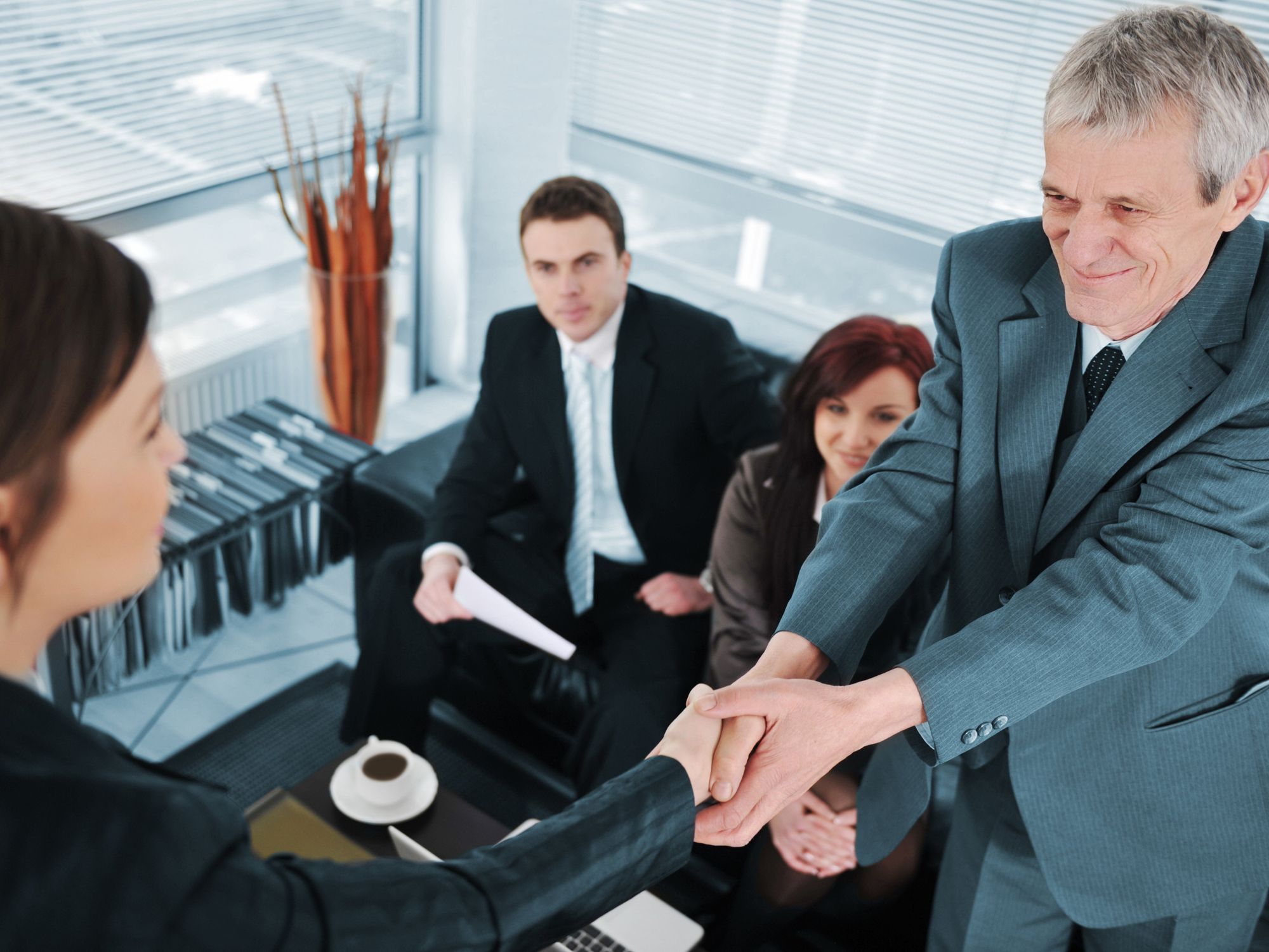Human resources shakes hands with job prospect during interview.