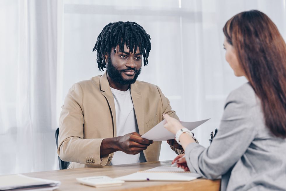 Job candidate hands the hiring manager his 30-60-90 day plan during an interview