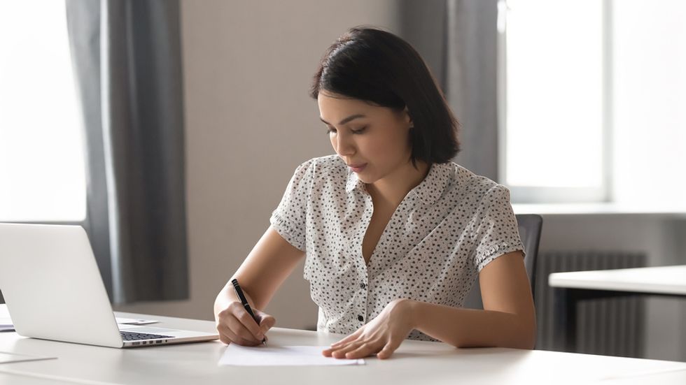 Job seeker on laptop writing an outstanding personal branding statement