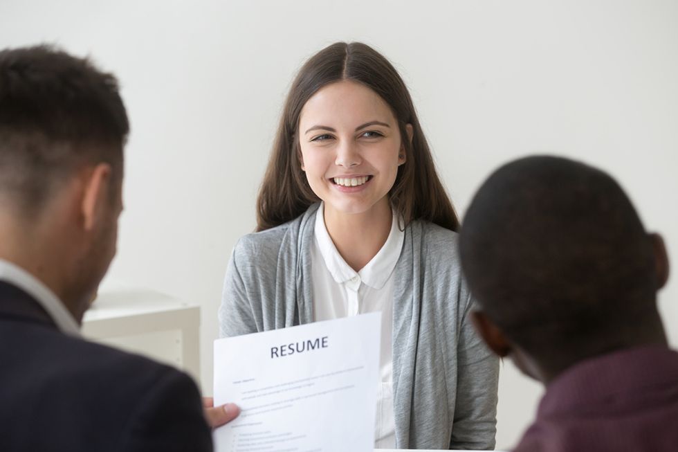 Job seeker smiles as two hiring managers read her well-written resume