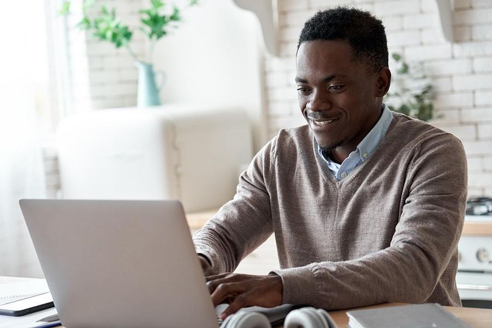 A job seeker writes his cover letter on his laptop
