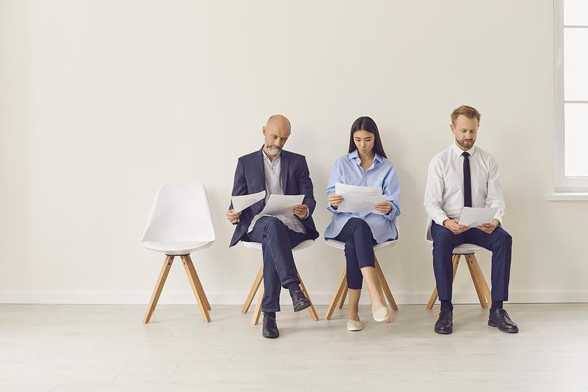 Job seekers read their resumes while waiting to talk to a staffing agency