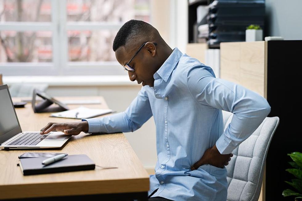 Man experiences back pain at his desk job