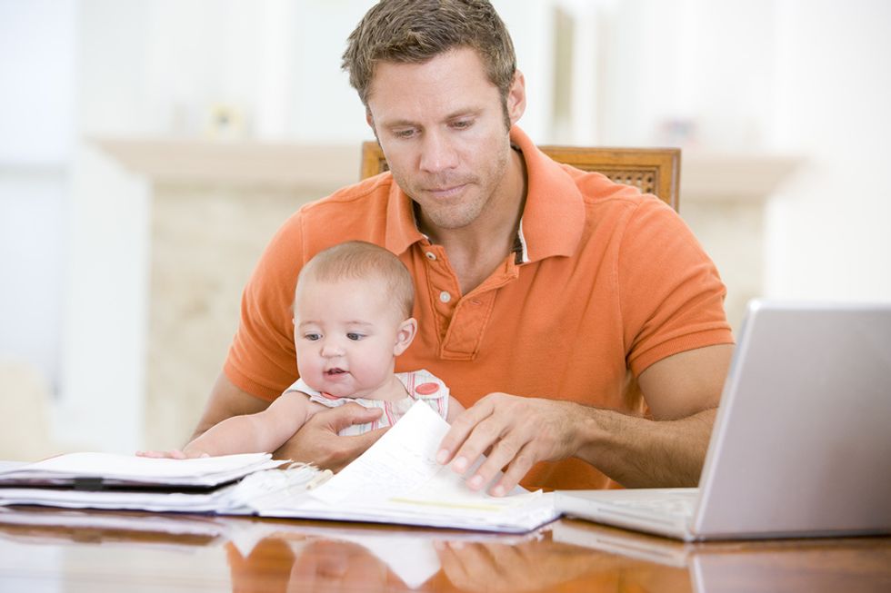Man holds his child while working from home