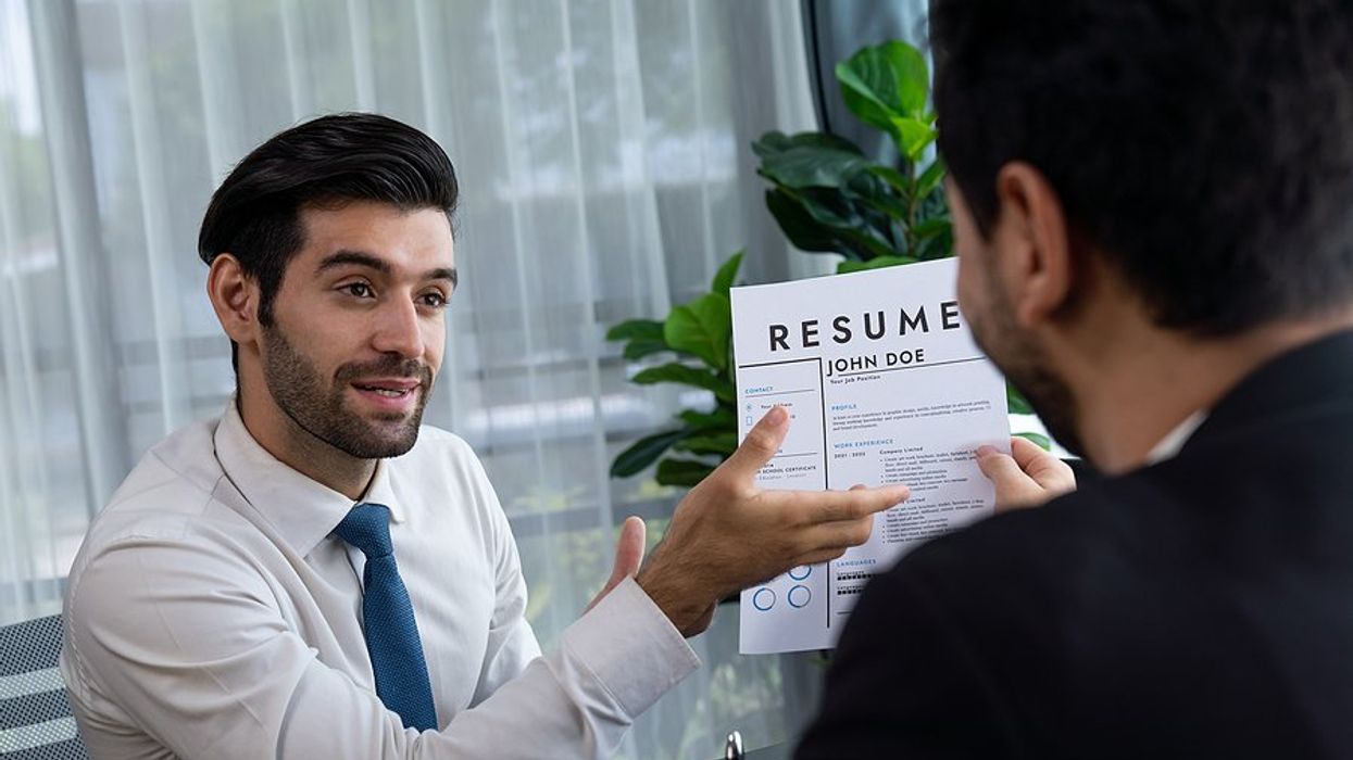 Man holds up his resume and answers the interview question, "How do you rate yourself?"
