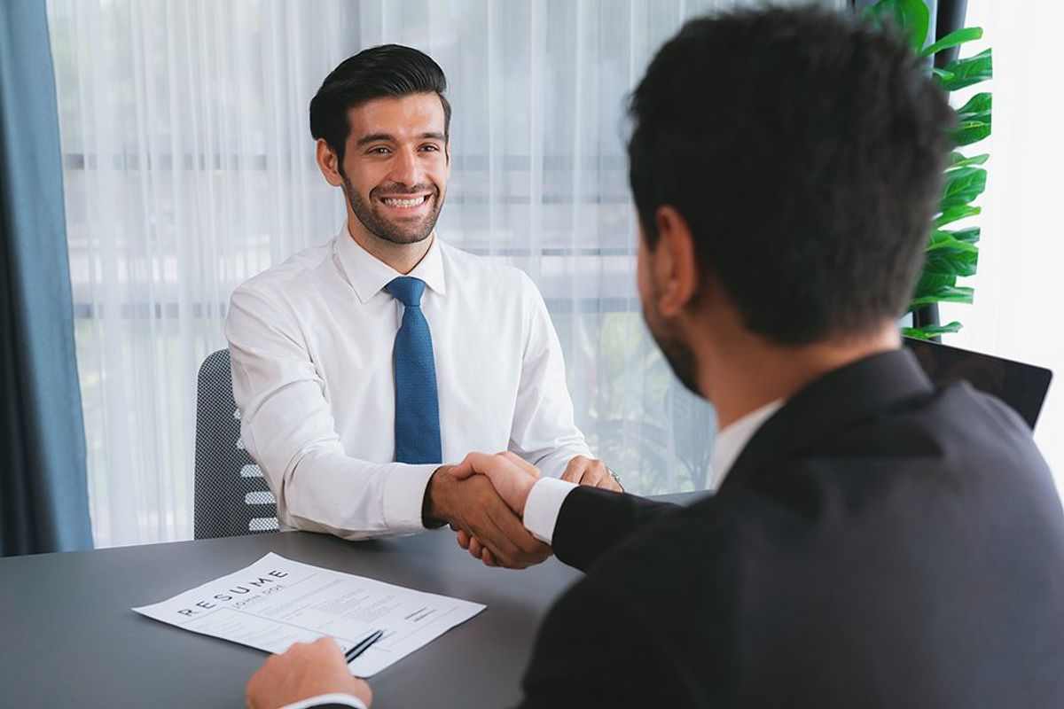 Man in a job interview shakes hands with the hiring manager after landing a higher-level job