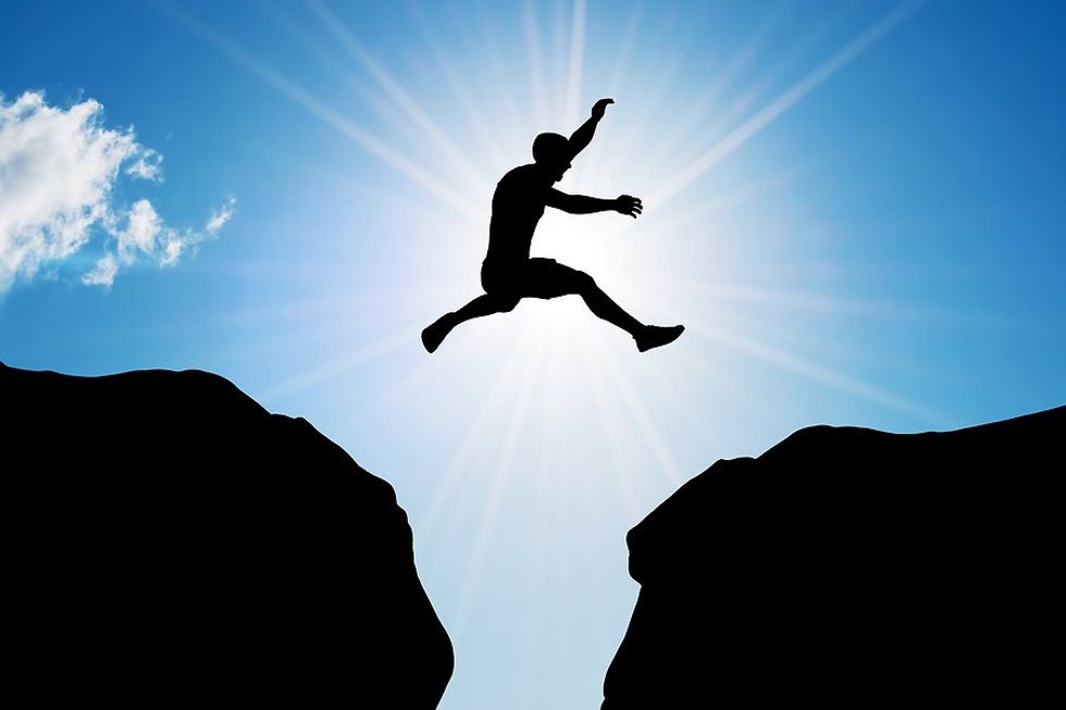 Man jumps/leaps across a cliff, risk concept