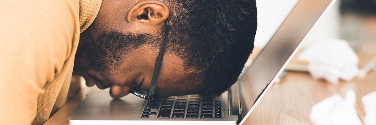 Man lacks confidence in his job search and puts his head down on his laptop