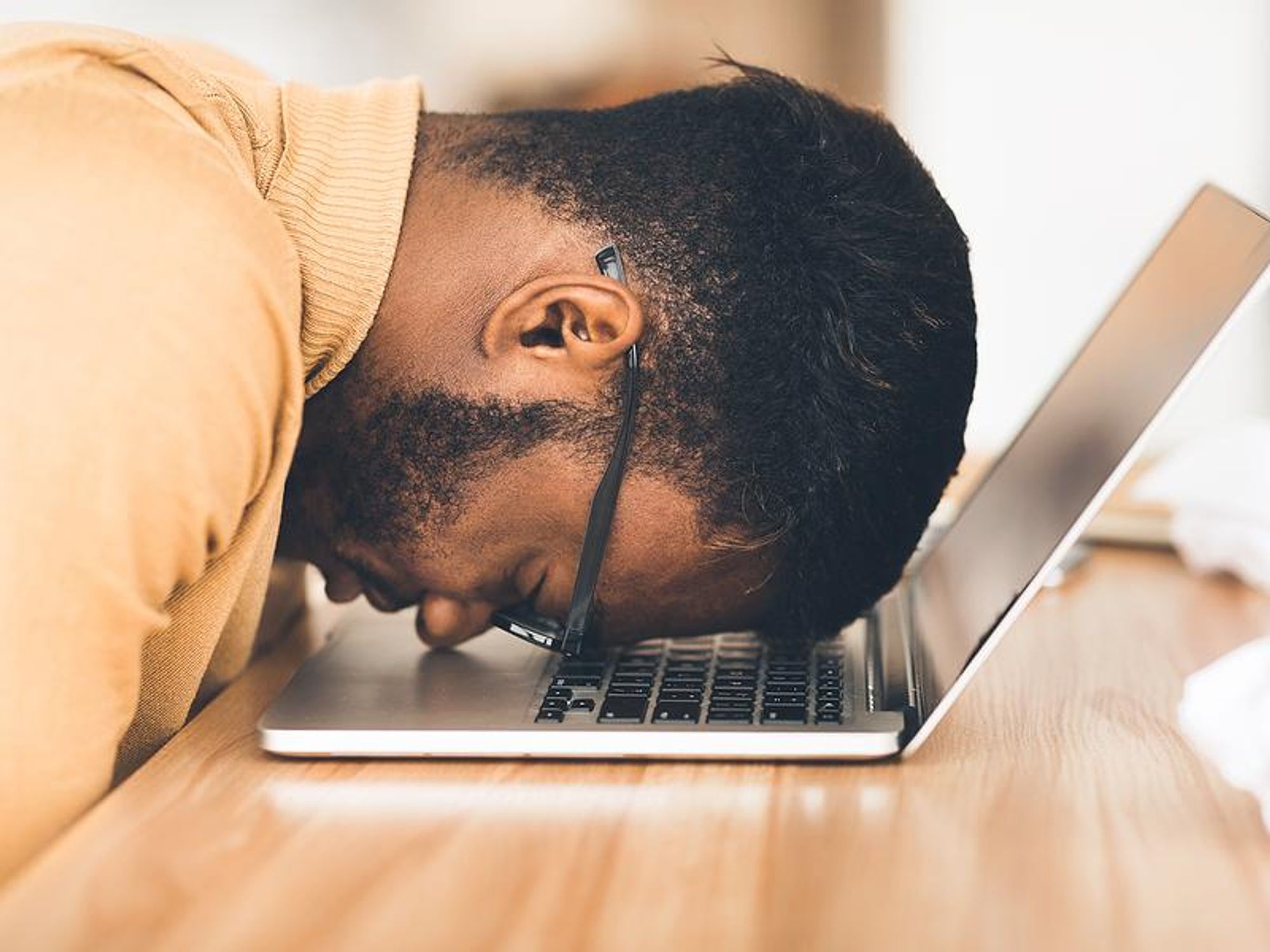 Man lacks confidence in his job search and puts his head down on his laptop