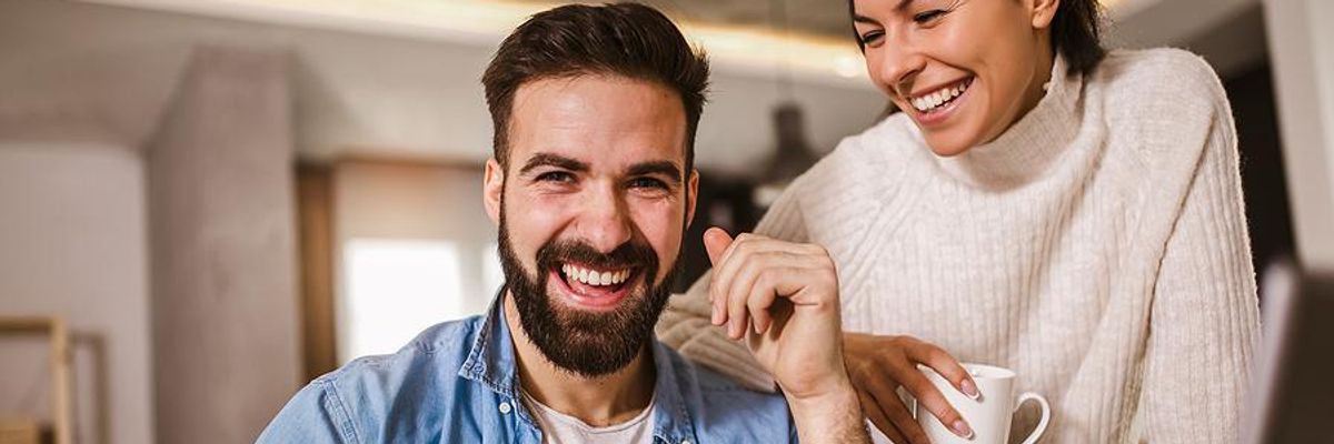 Man laughs with his wife while working from home in the summer