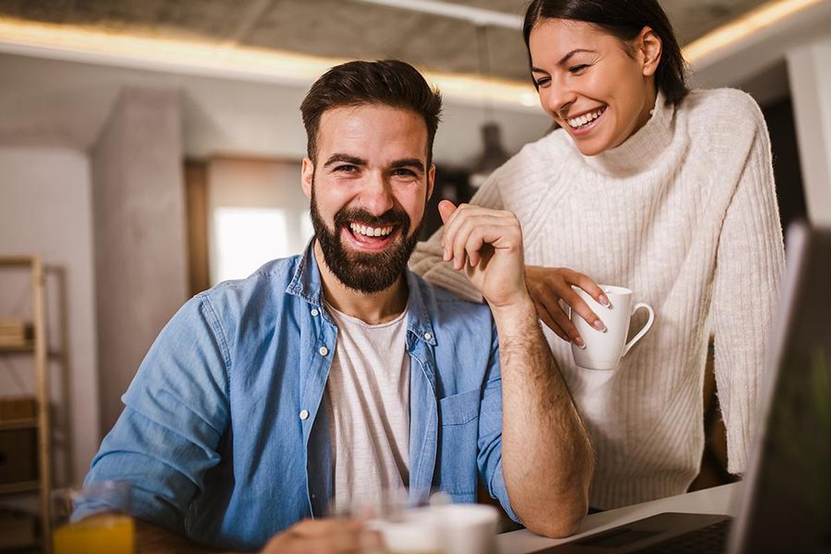 Man laughs with his wife while working from home in the summer