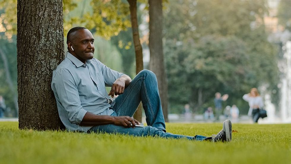 man sitting in park listening to podcast