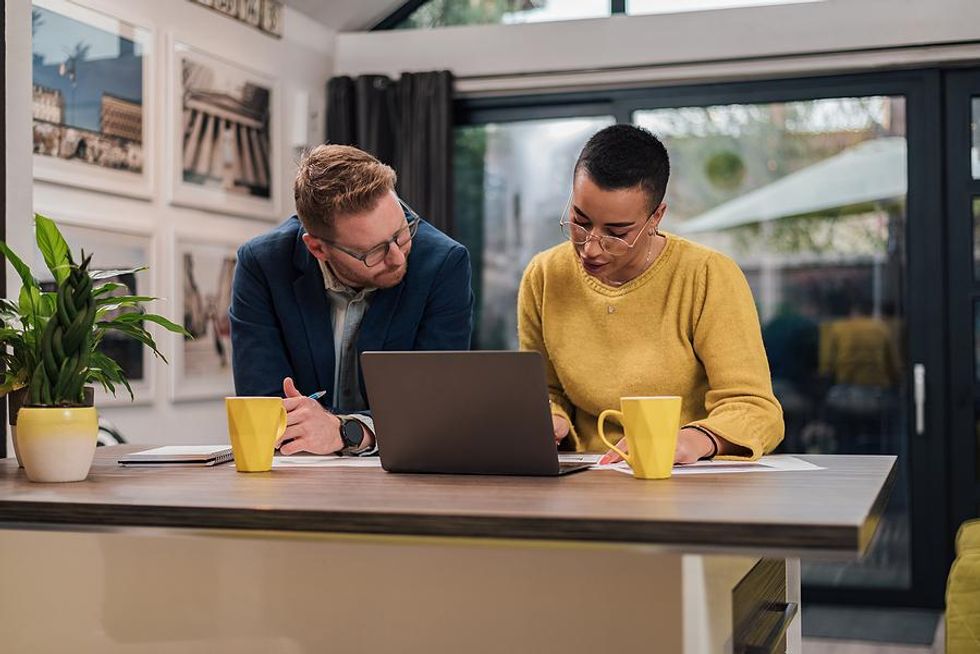 Man listens to his coworker while they work on a project together