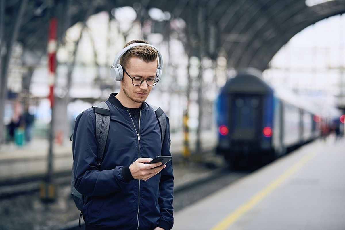 Man listens to uplifting podcast episodes while waiting for a train