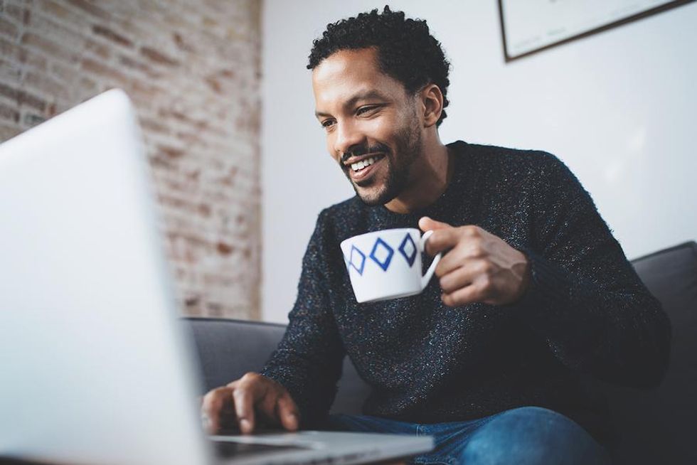 Man looks for a job on his laptop while drinking coffee