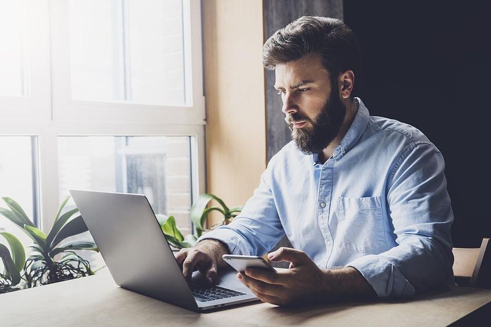 Man looks something up on his laptop and phone