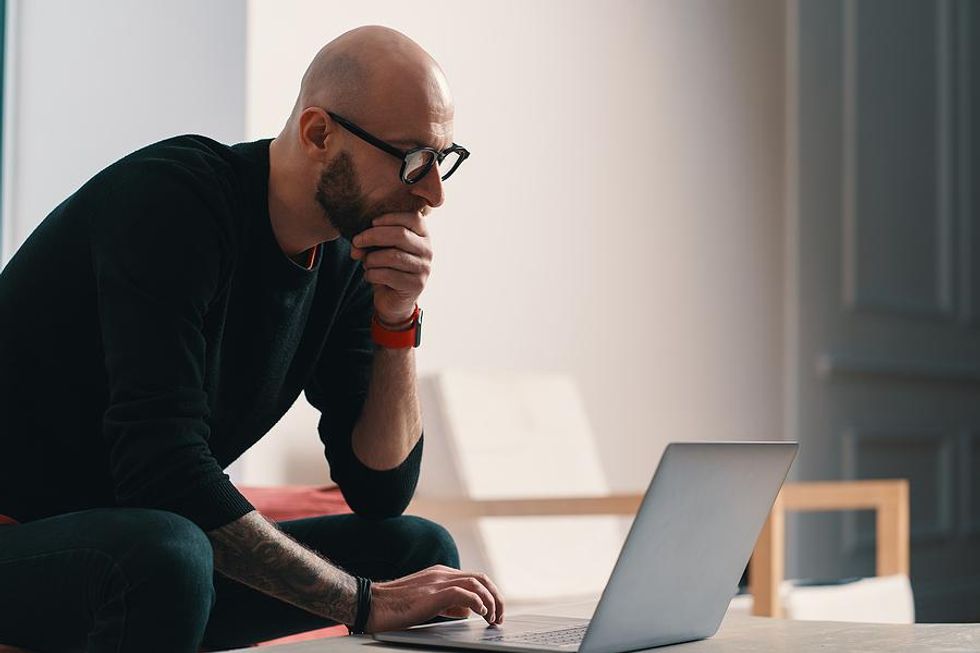 Man on laptop edits his resume after getting fired