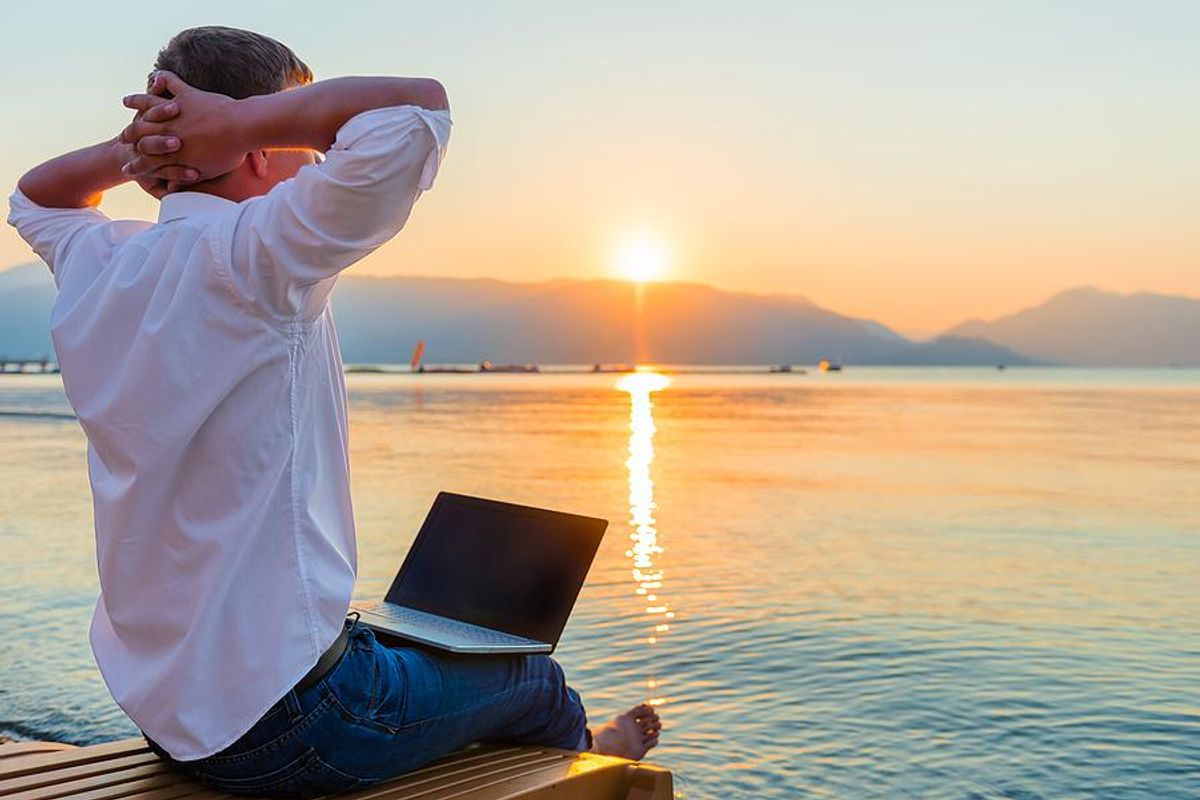 Man on laptop enjoys summer while working full time