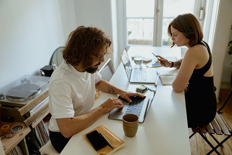 Man on laptop looks for a job while his partner works from home